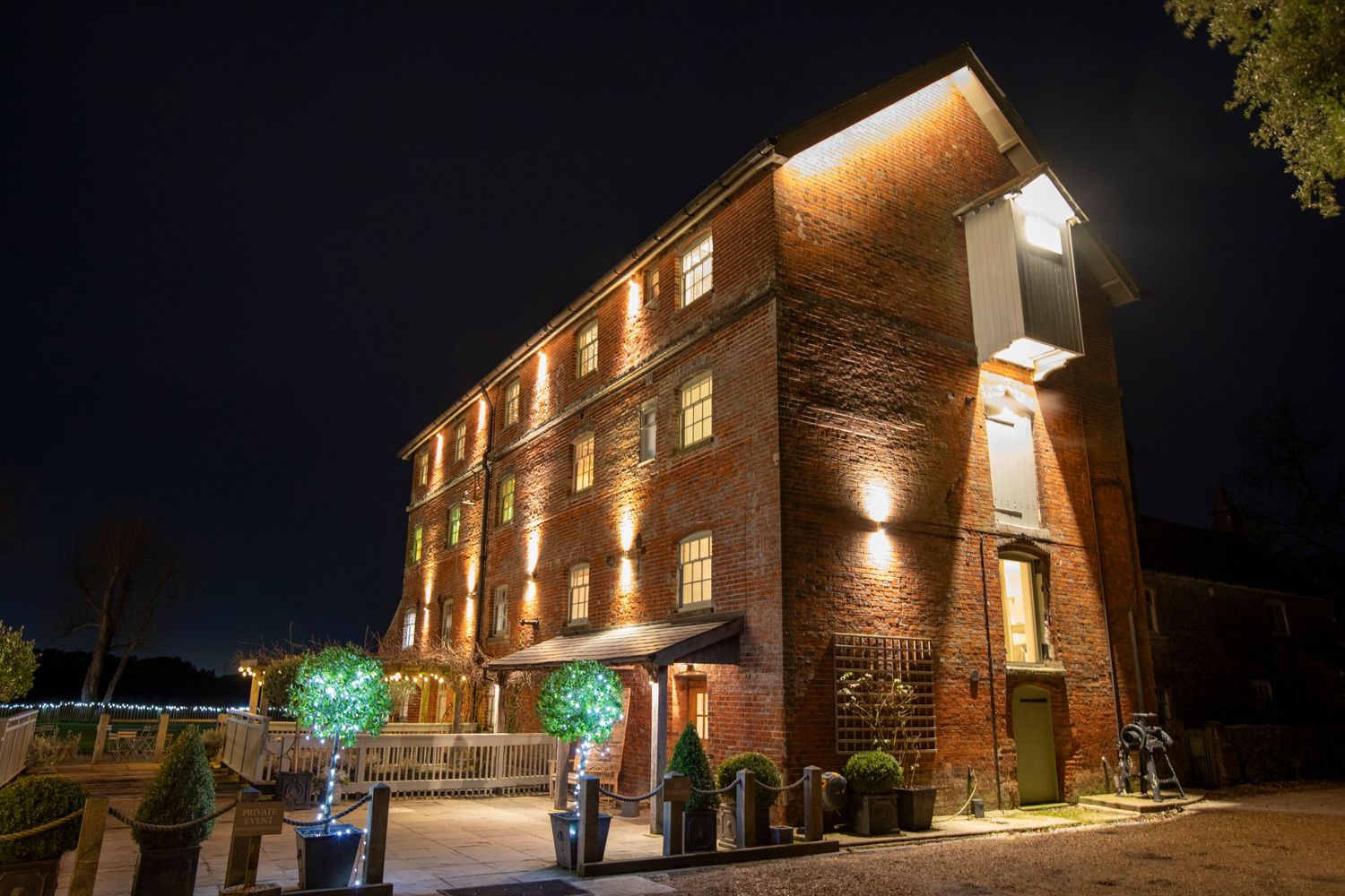 Exterior nighttime view of a brick wedding venue with illuminated landscaping.