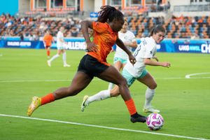 Soccer players in orange and white uniforms compete for ball possession during an intense match.