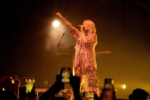 Concert performance with dramatic orange stage lighting and fog effects.