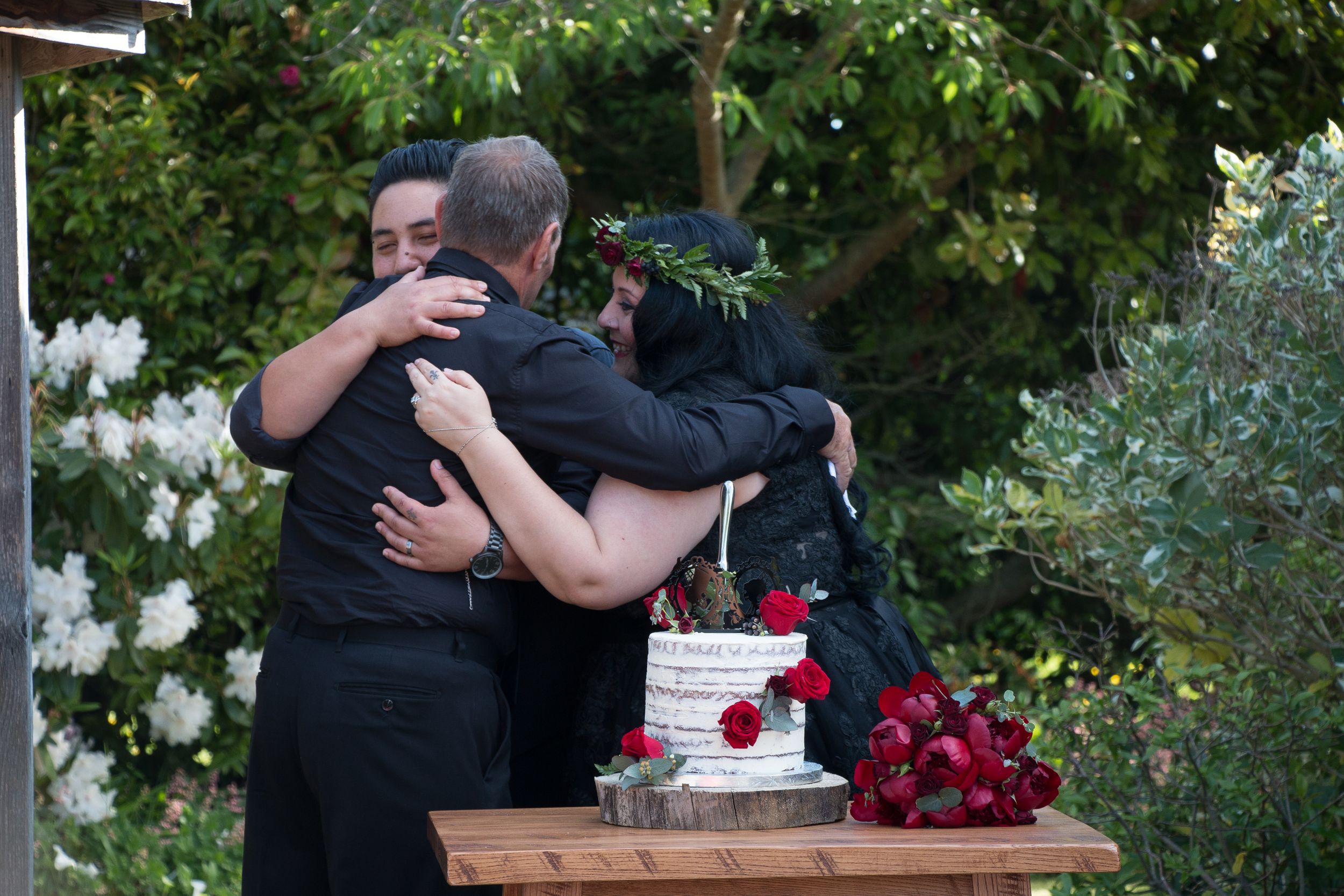 Wedding party members share an emotional group hug next to the cake table.