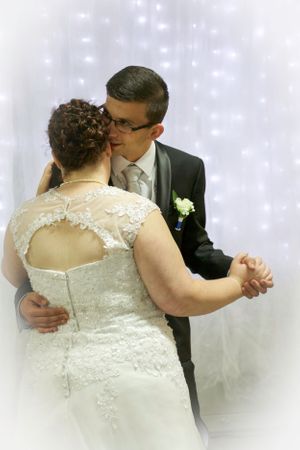Couple embraces during their first dance with twinkle lights in background.
