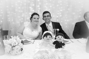 Newlyweds at their reception table with decorative bride and groom dolls.