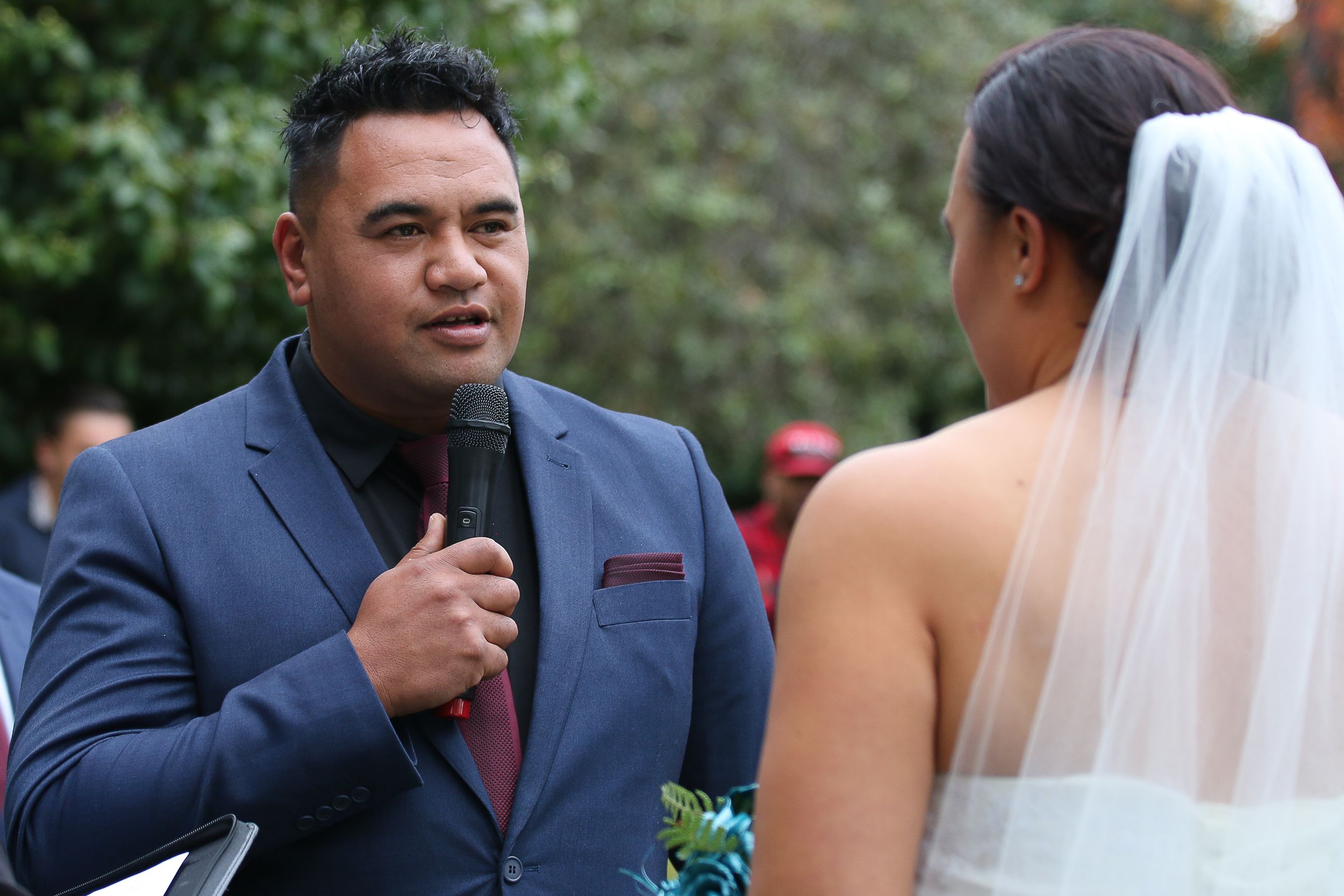 An outdoor wedding ceremony features heartfelt vows being exchanged.