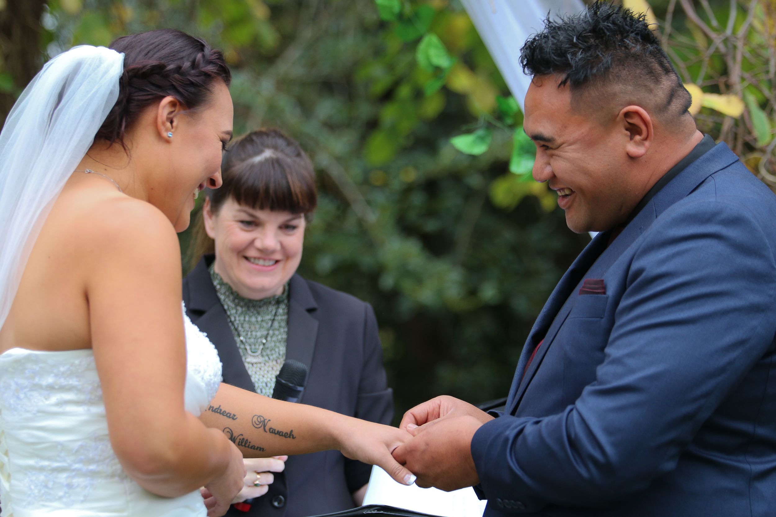 A wedding ceremony captures the exchange of rings during an intimate outdoor service.