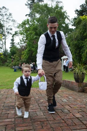 A heartwarming moment between two formally dressed figures walking on brick pavement.
