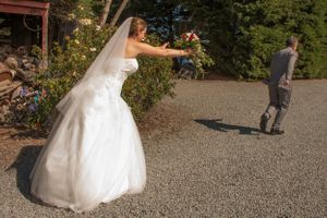 A person in a flowing white wedding dress plays a fun game in an outdoor garden setting.