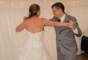 A couple shares their first dance at a wedding reception under string lights.