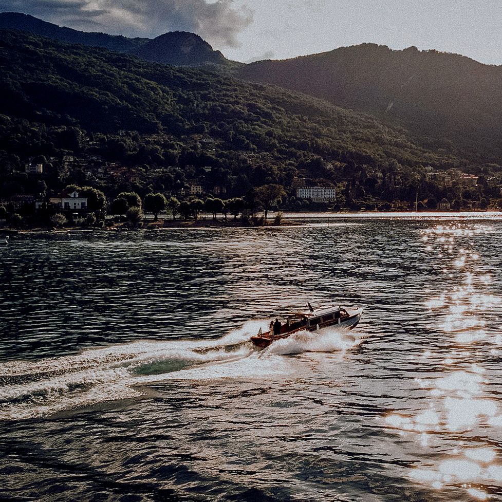 Speedboat cutting through sparkling lake waters with sunlit mountain backdrop at golden hour.