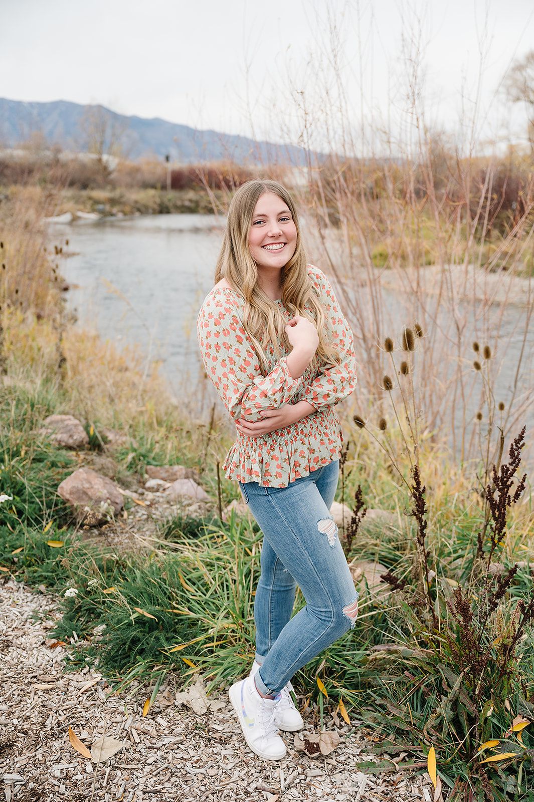 A portrait in a natural setting with autumn grasses and a flowing stream in the background.