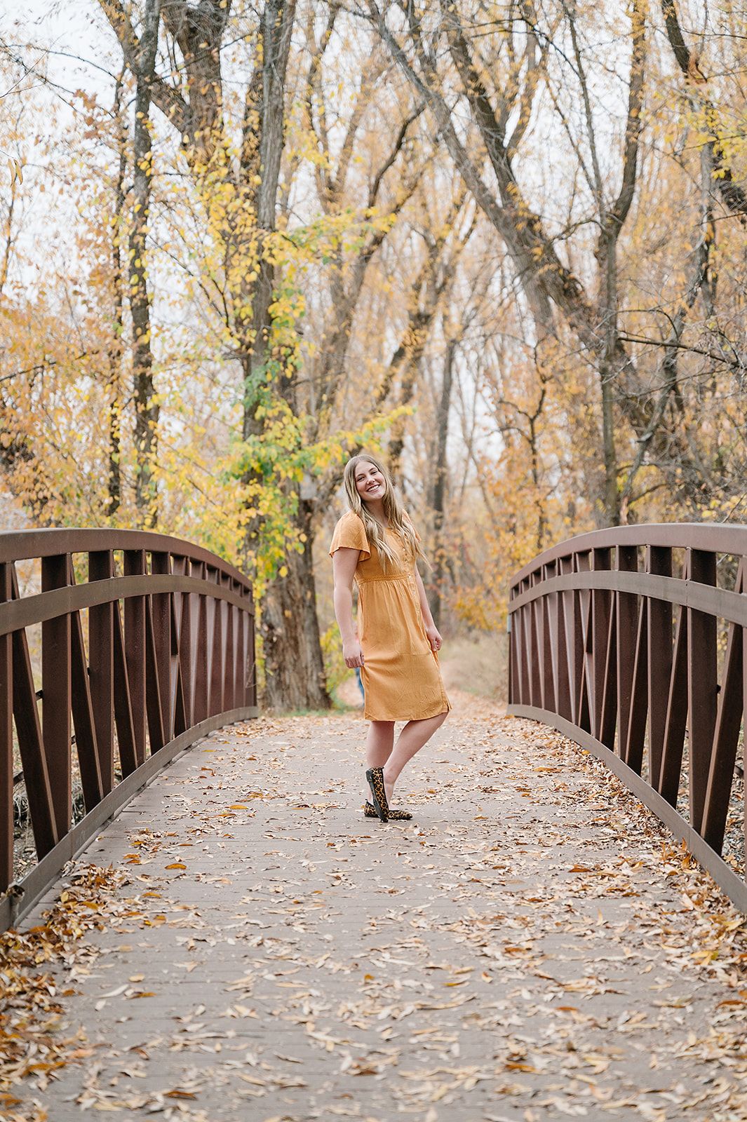 A fashionable autumn portrait on a wooden bridge covered with fallen leaves.
