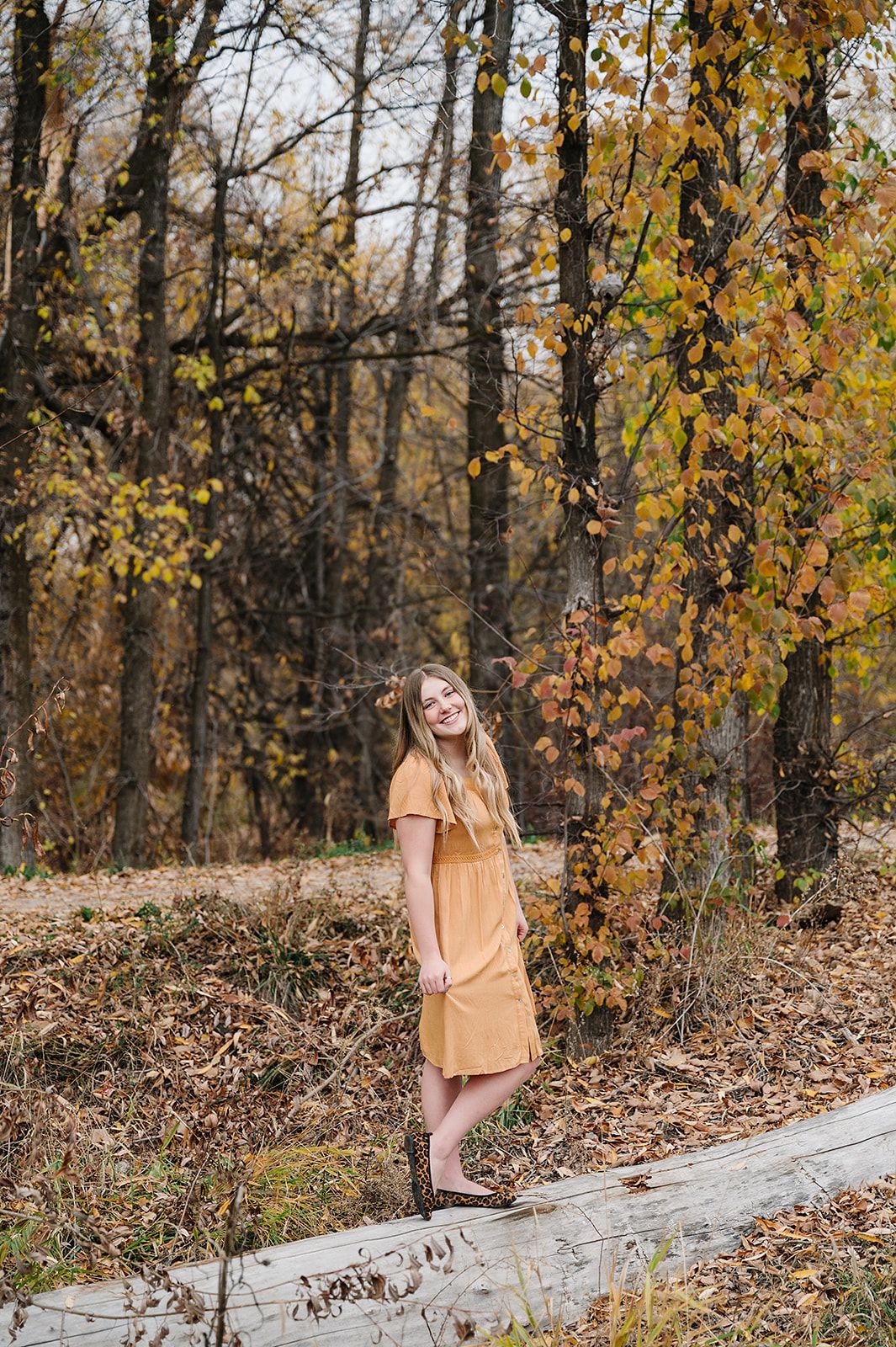 A cheerful autumn portrait among golden leaves and fallen logs in the woods.