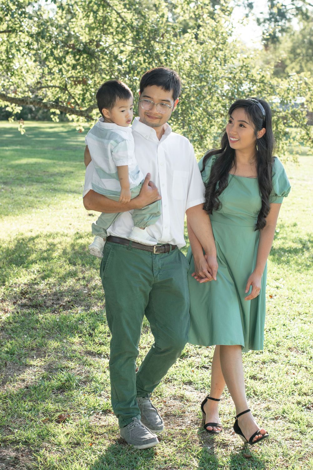 A family poses together outdoors wearing coordinating green and white outfits.