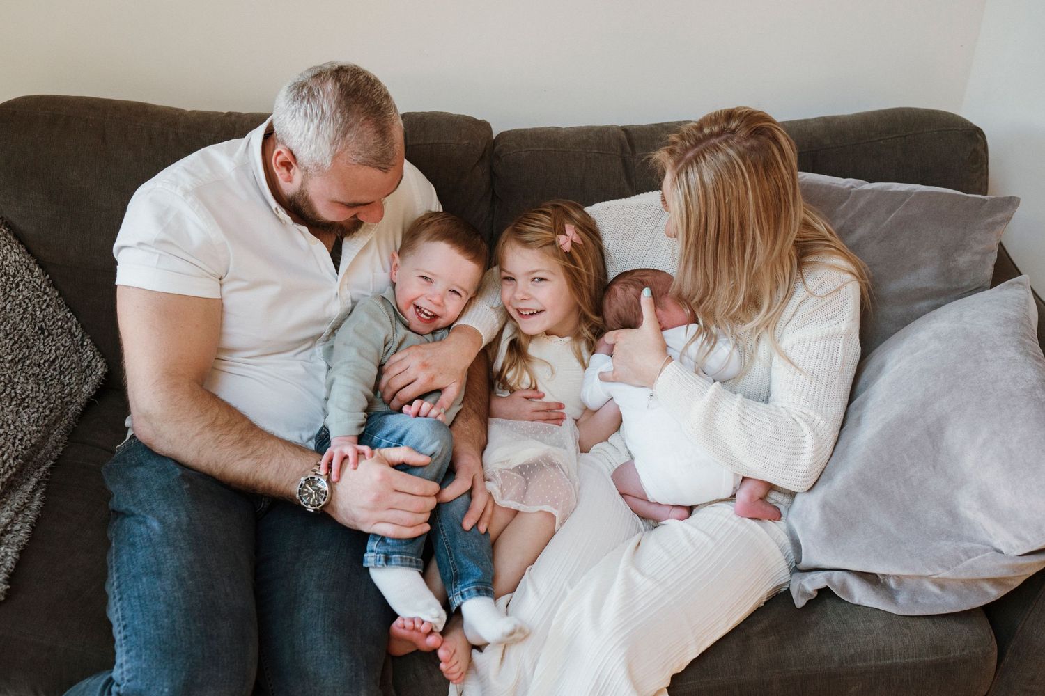Family relaxing together on a cozy grey couch during an intimate home photoshoot.