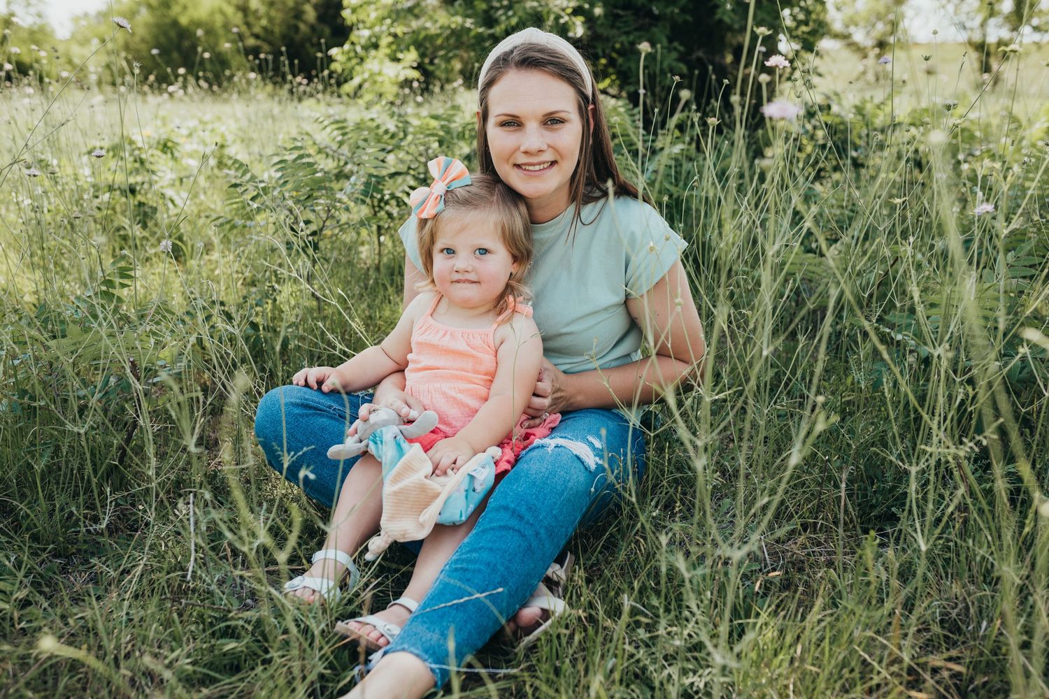 Mommy and daughter sitting in a field