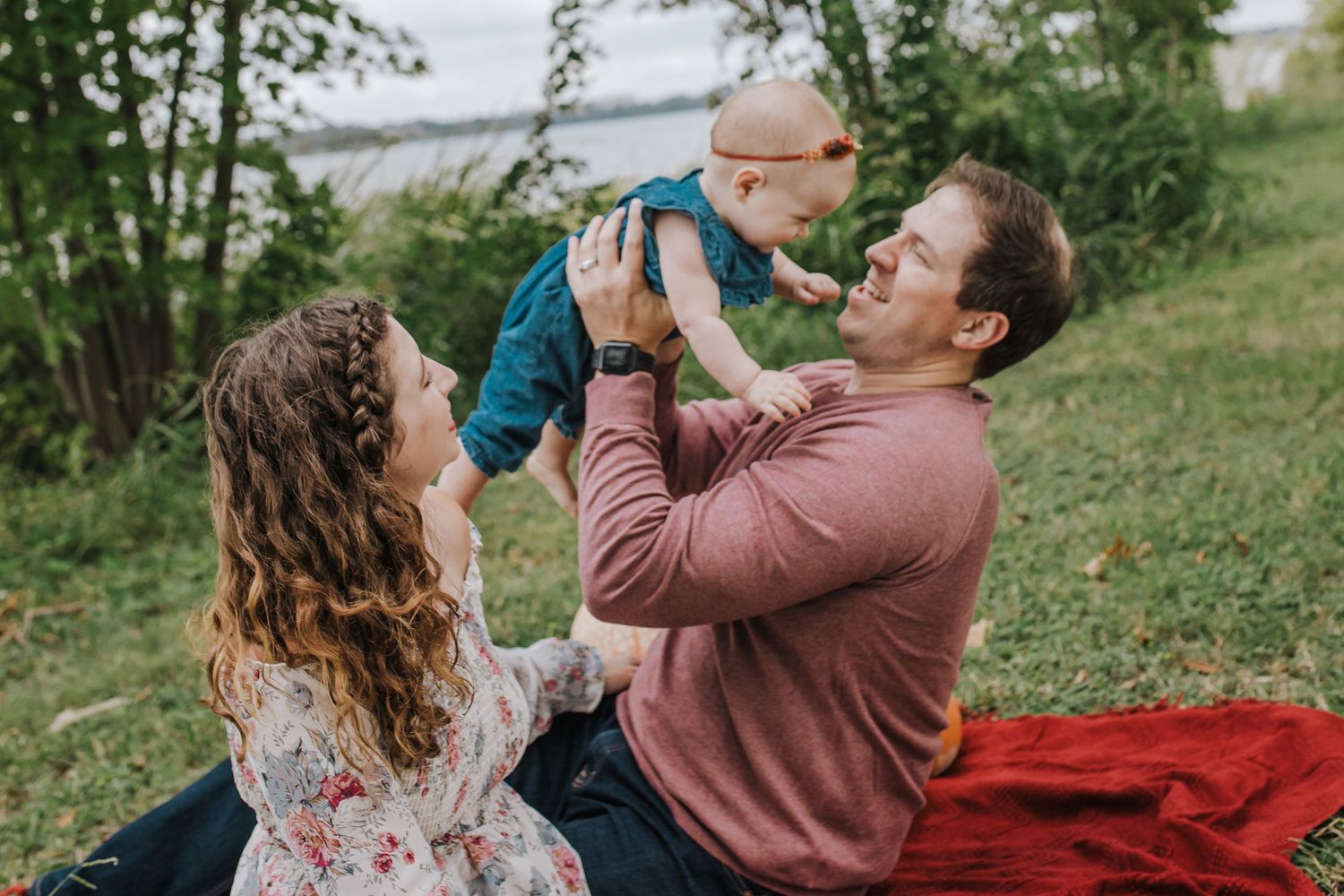Family of three sitting by white rock lake
