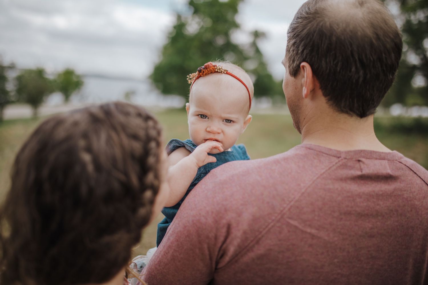 one year old looking back over mom and dads shoulders
