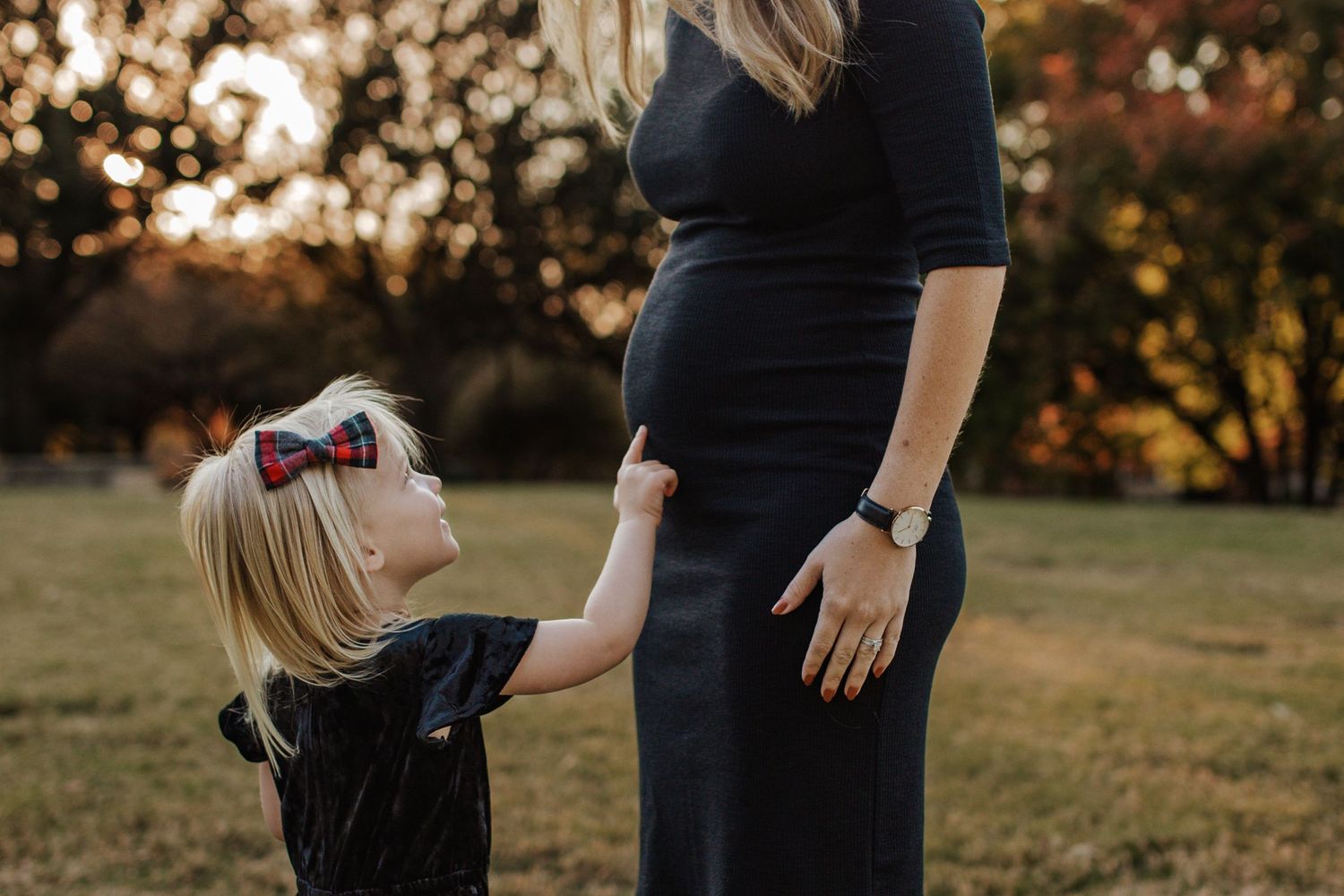 Toddler pointing to mommy pregnant belly at golden hour