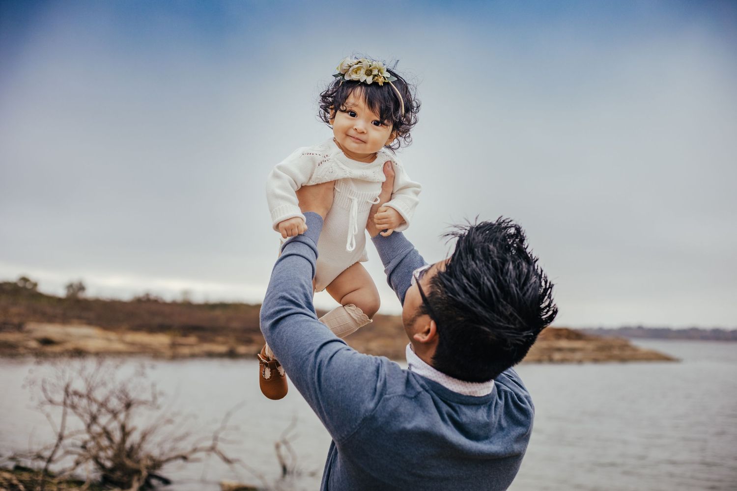Dad holding baby in the air by the water
