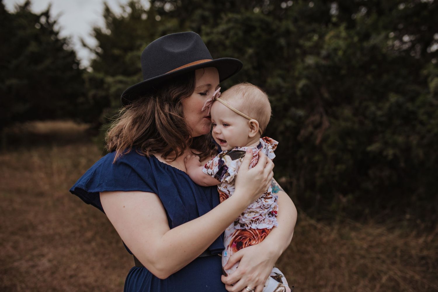 mom kissing one year old daughter at Pecan Grove Park