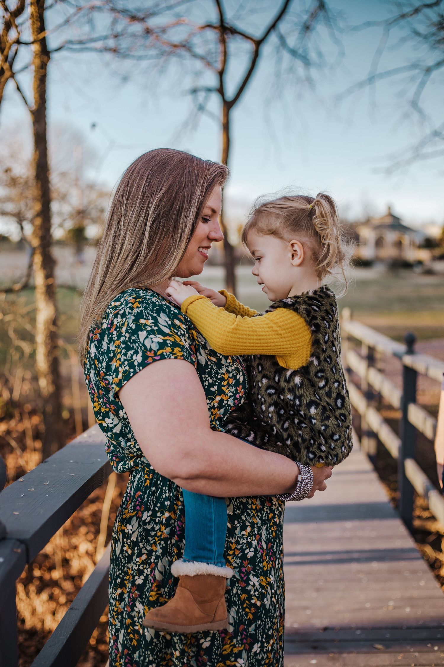 three year old girl with mom standing by a walking bridge