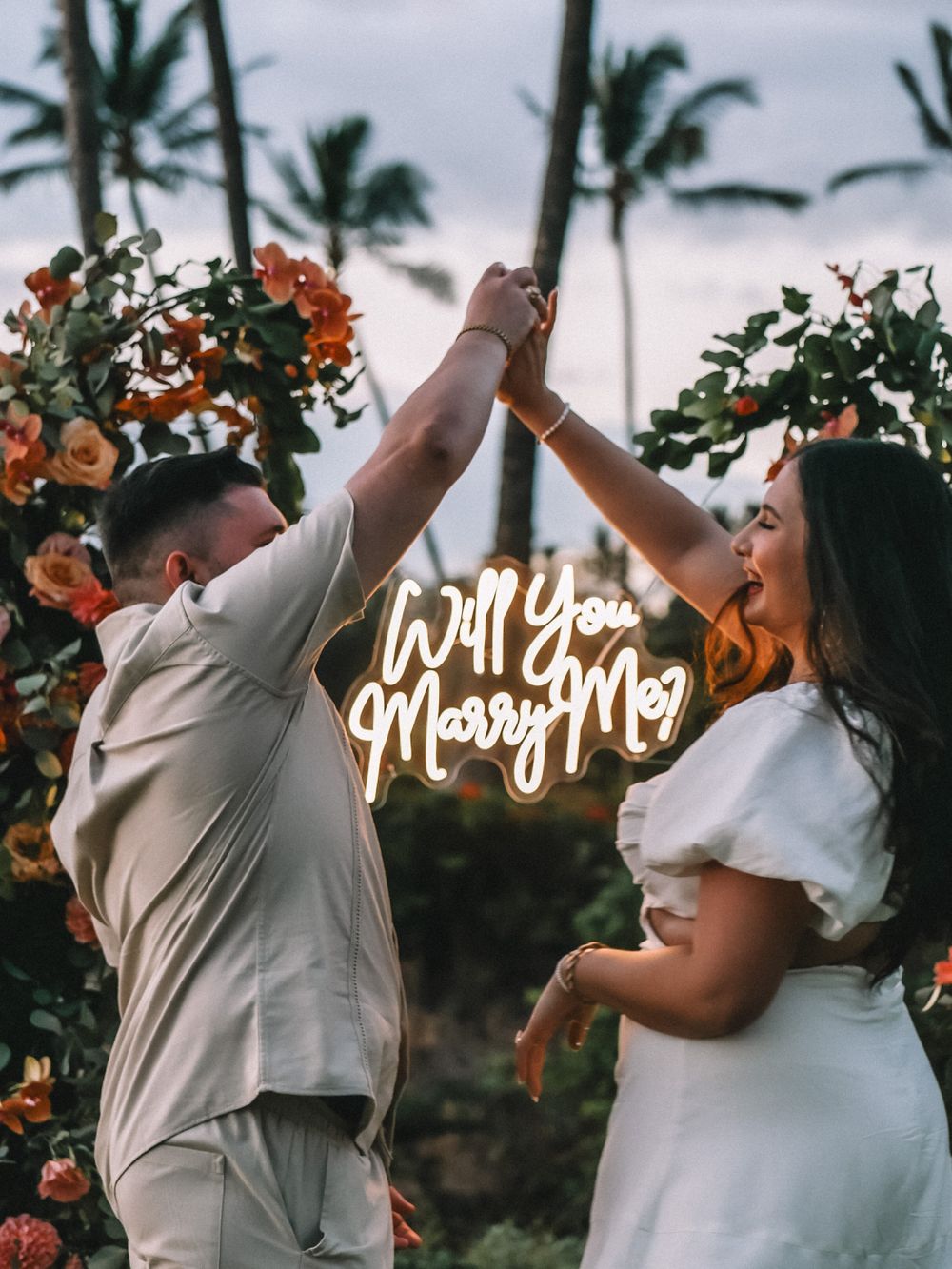 Celebratory wedding moment against a backdrop of palm trees and orange sunset sky.