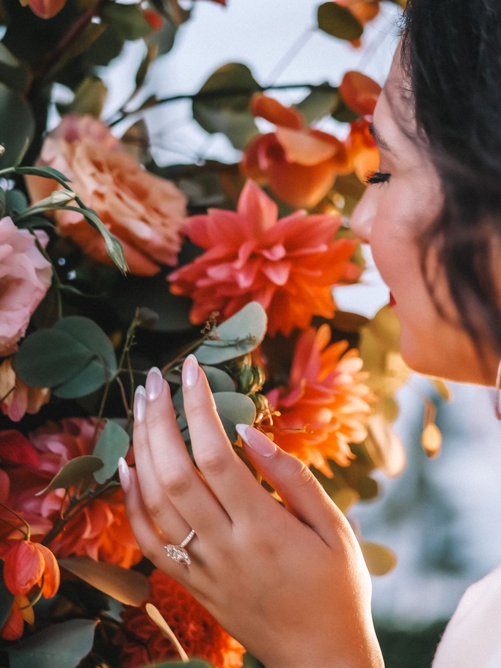 Close-up shot of hands reaching for vibrant orange flowers against a blurred background.