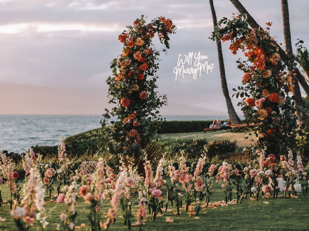 Scenic beach landscape with palm trees and floral arrangements at sunset.