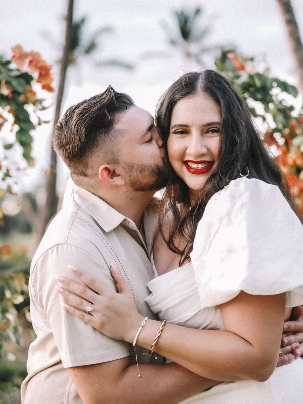 Joyful embrace captured during a beach wedding photoshoot with tropical florals.