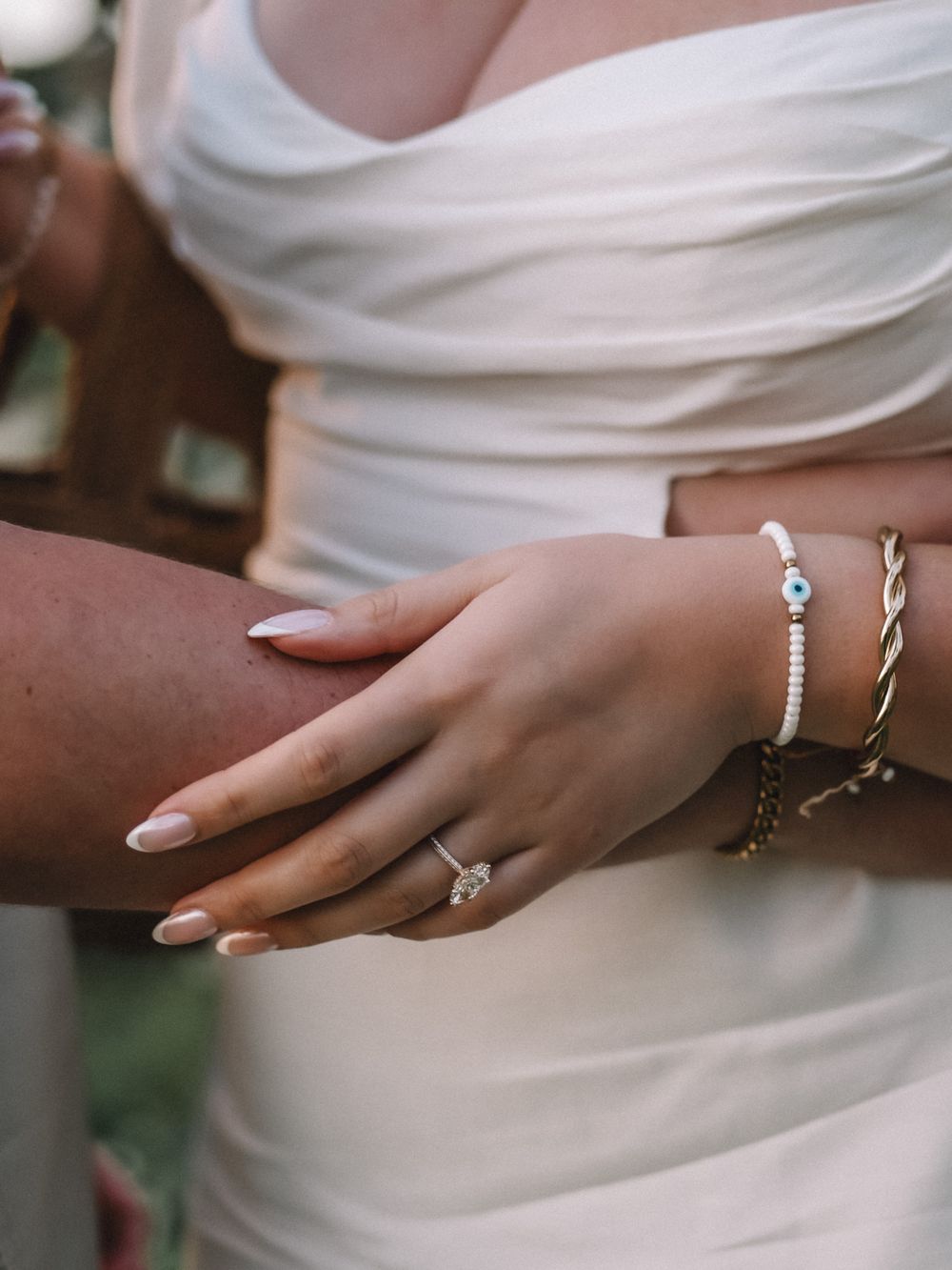 Close-up of delicate bridal jewelry and accessories against white fabric.