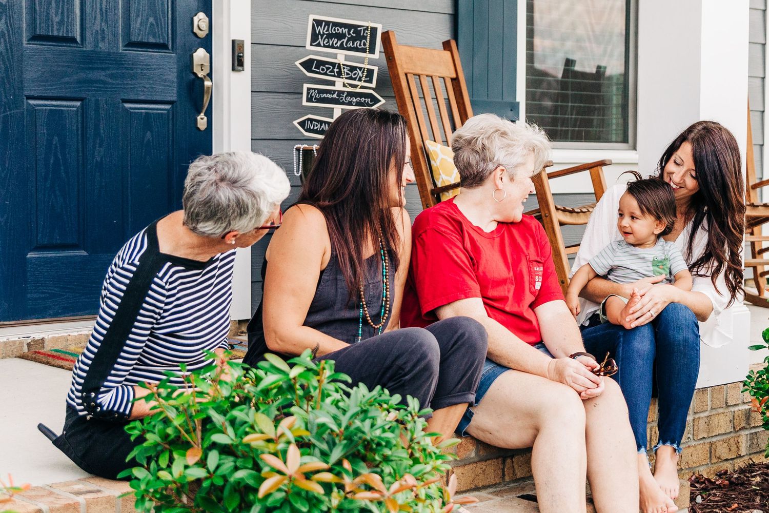 Family sitting with a young boy on the front porch smiling