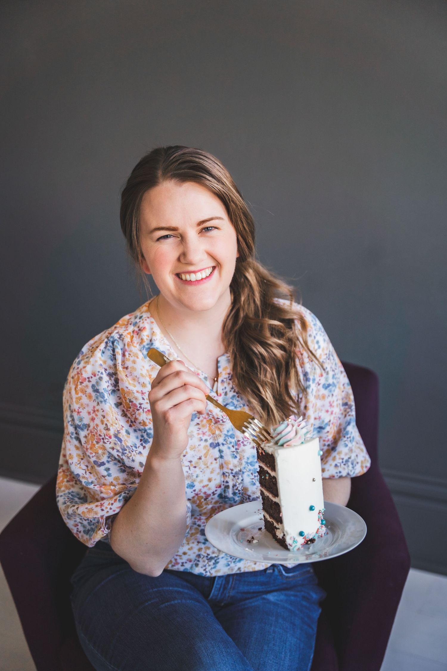 A person enjoys eating cake while sitting in a comfortable armchair.