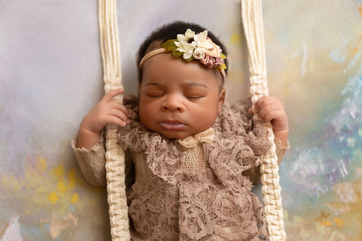 A sleeping baby rests in a swing decorated with vintage lace and floral details.