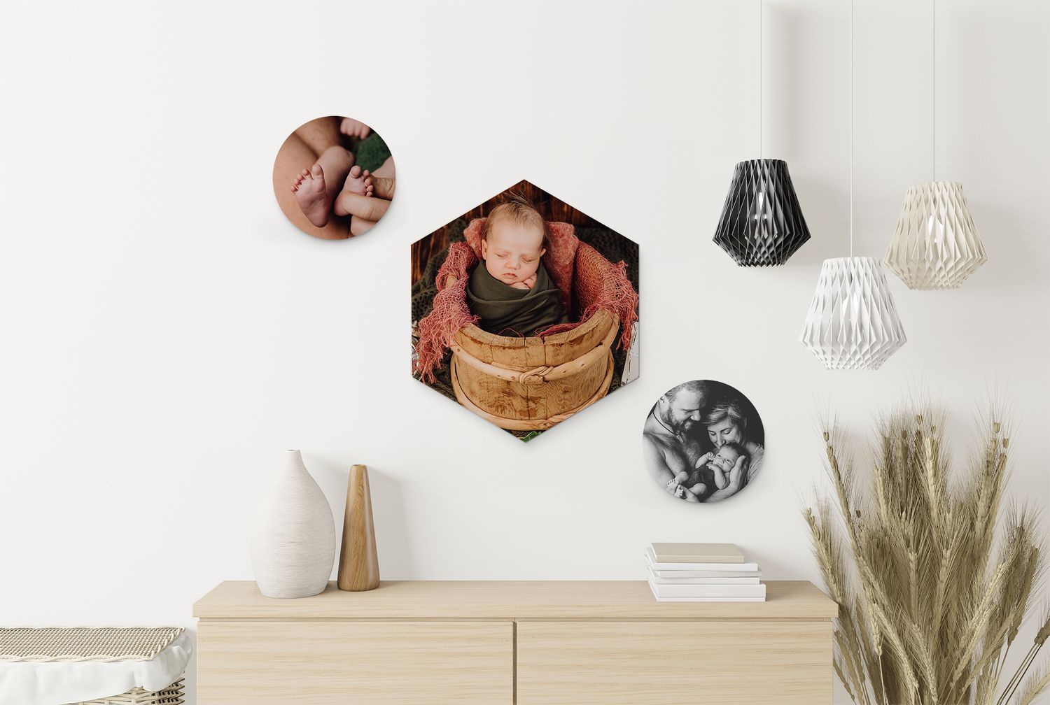 Modern wall display with hexagonal photo tiles and pendant lights above wooden dresser with dried pampas grass.