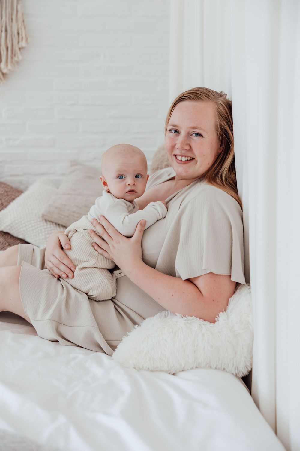 A tender moment between parent and baby on a cozy white bed.