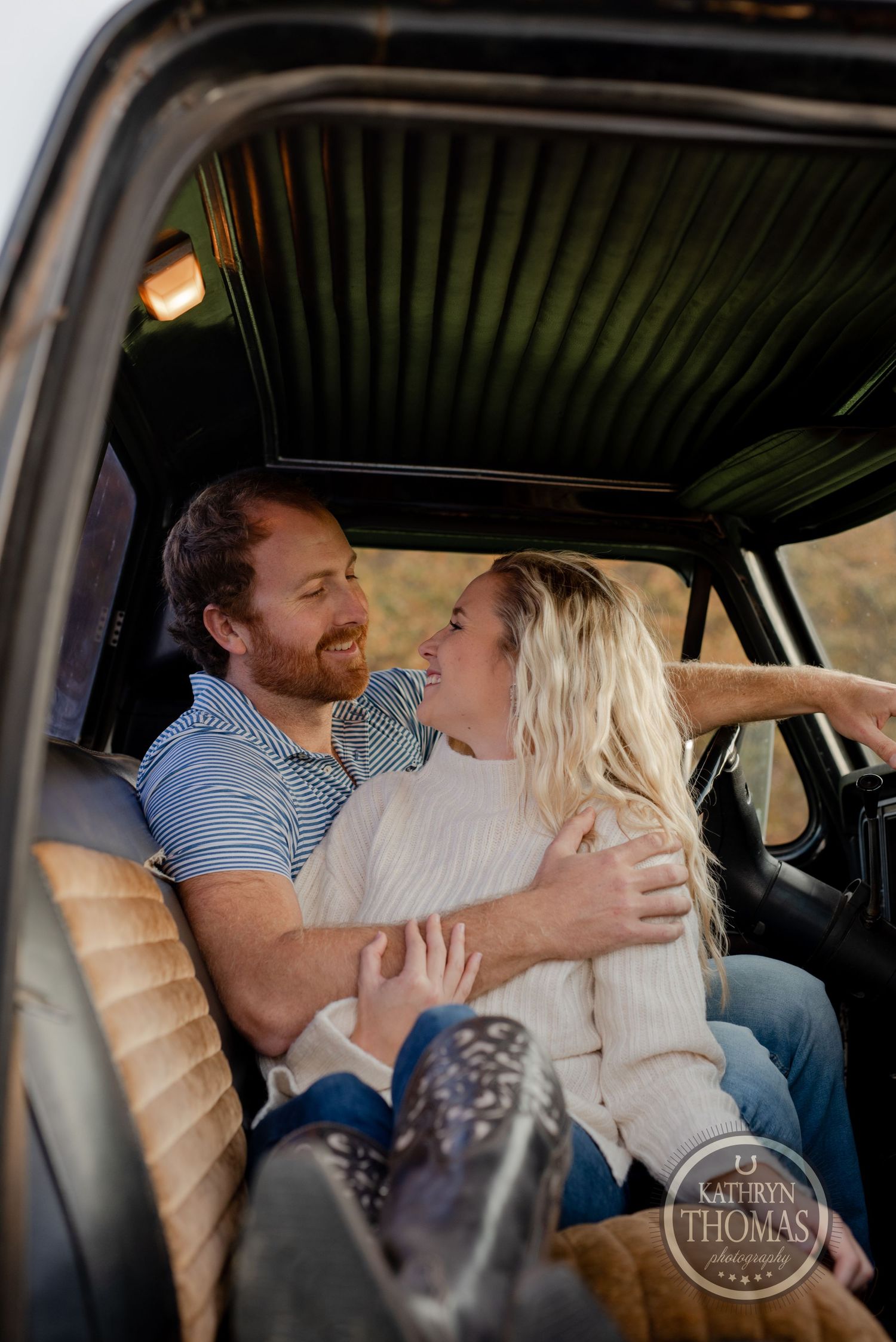 Candid moment of laughter shared between a couple inside vintage truck with tan leather seats.