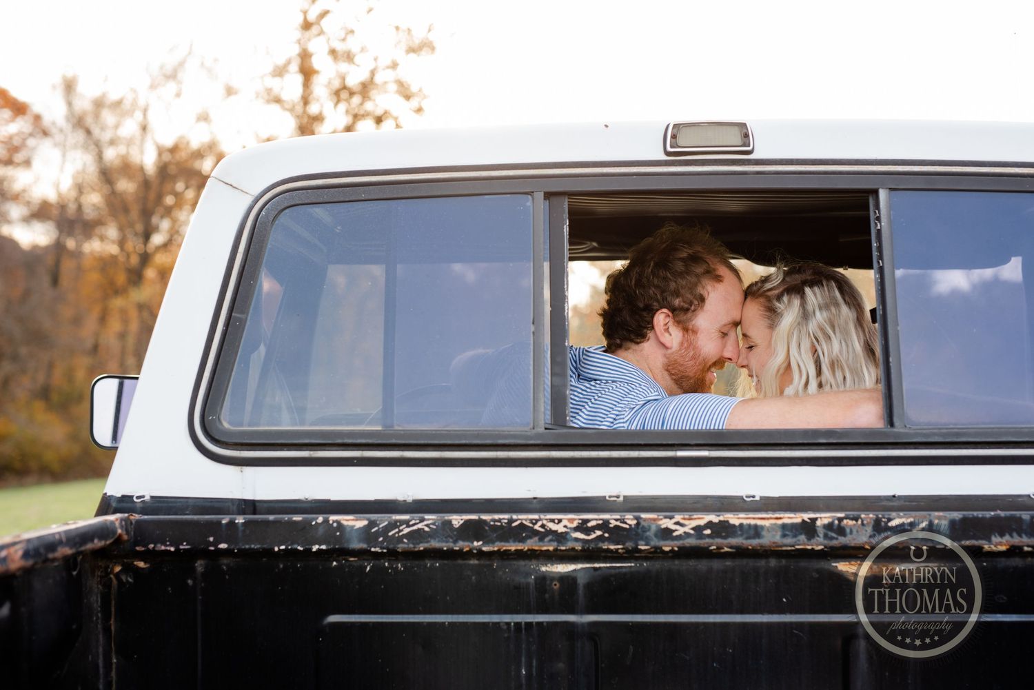 Couple sharing an intimate moment through the window of a classic black pickup truck.