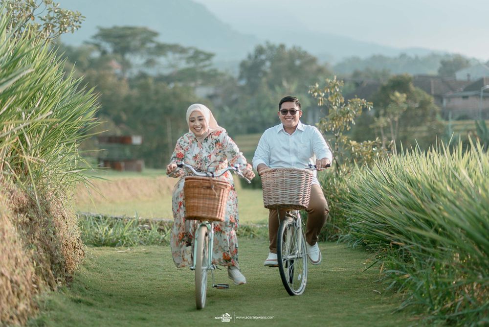 A couple rides bicycles together along a scenic mountain path.