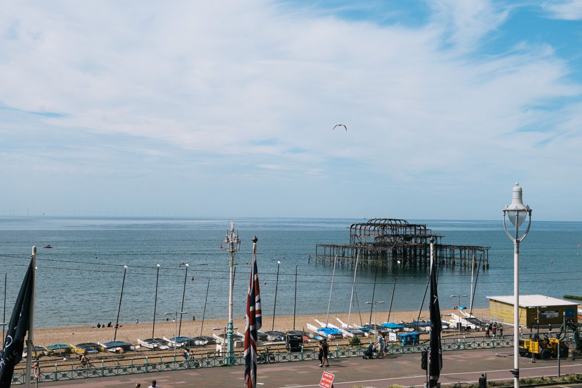 Seaside pier with beach chairs under blue skies and seagulls flying overhead.