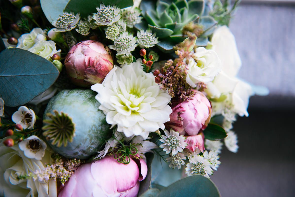 Close-up of a romantic wedding bouquet with pink peonies, white dahlias, and eucalyptus.