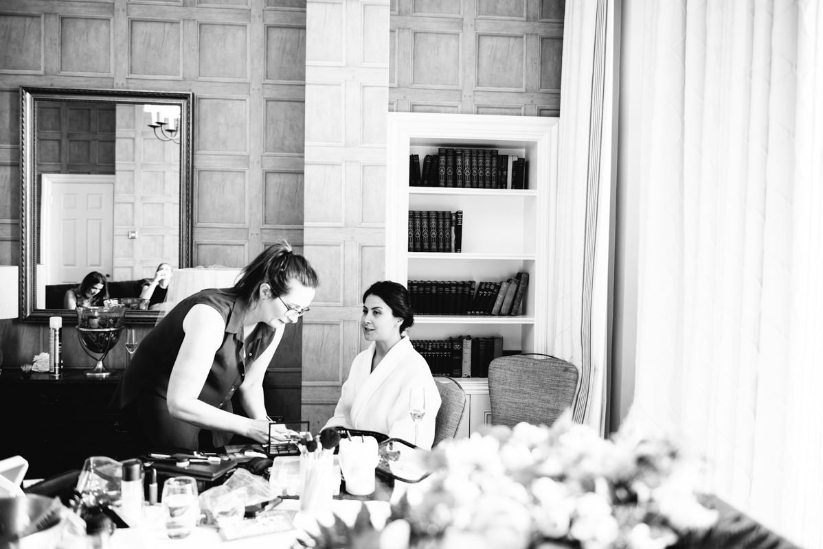 Black and white photograph of wedding preparation in a wood-paneled room.