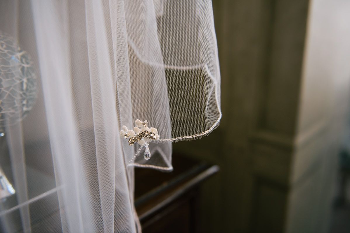 Close-up of delicate white wedding veil detail with floral embellishment.