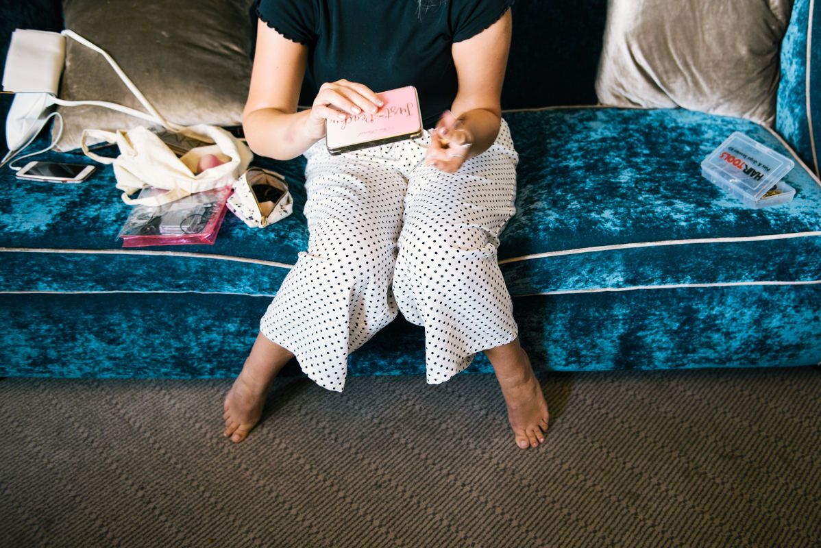 Person sitting on blue velvet couch holding white lace fabric.