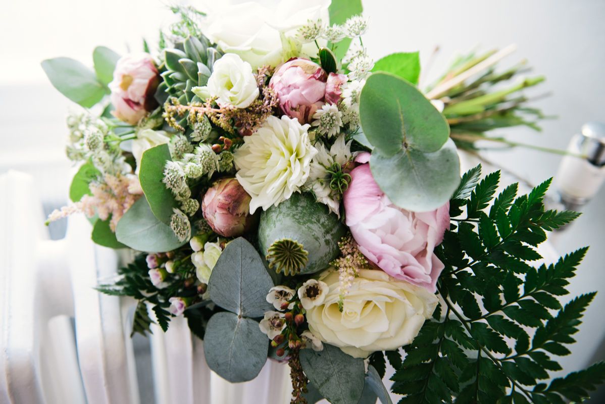 Elegant wedding bouquet with pink and white roses, eucalyptus leaves, and ferns.