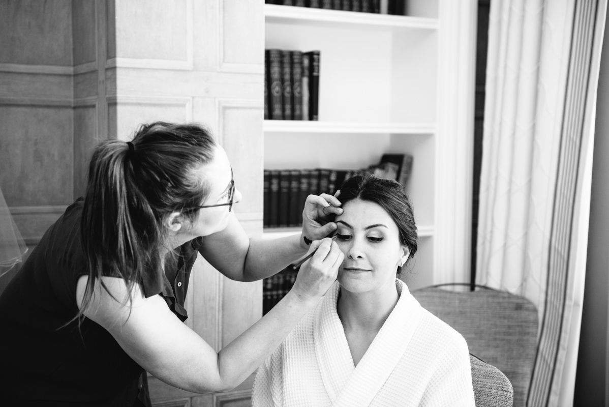 Professional makeup artist applying cosmetics during wedding preparation.