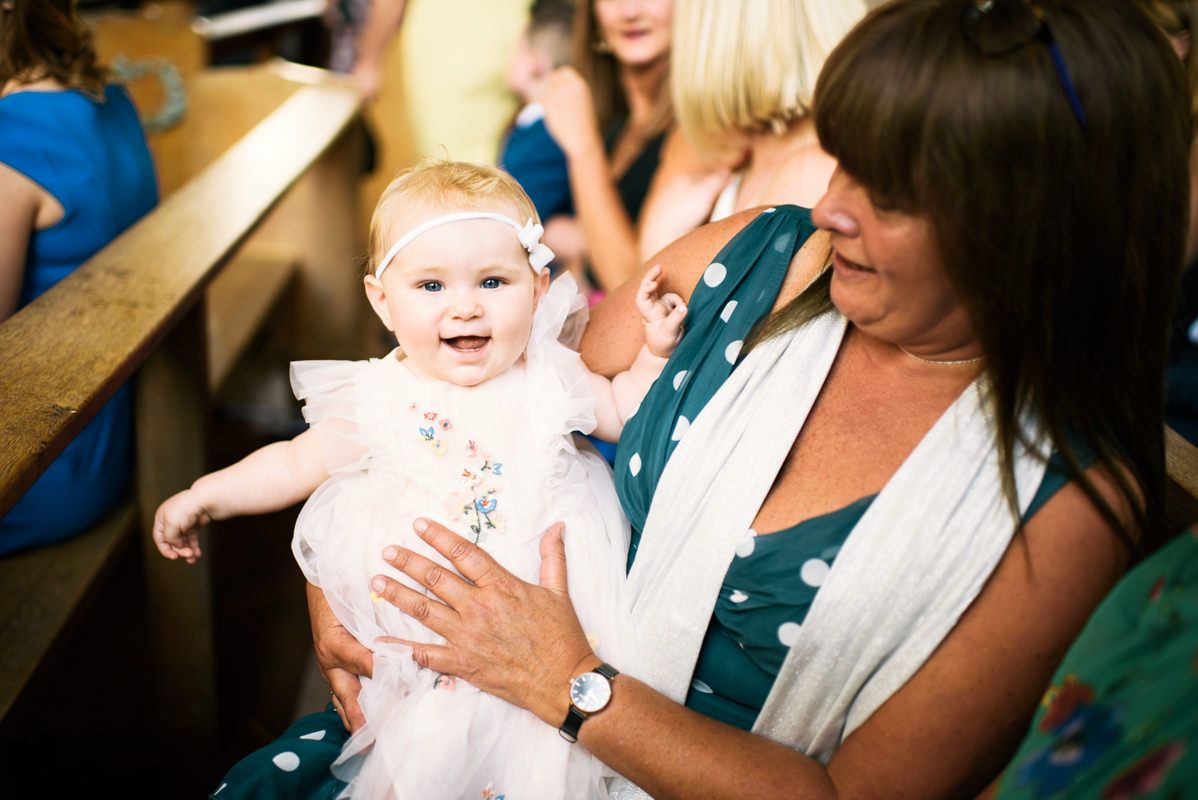 A baby smiles joyfully during a candid moment at a celebration.