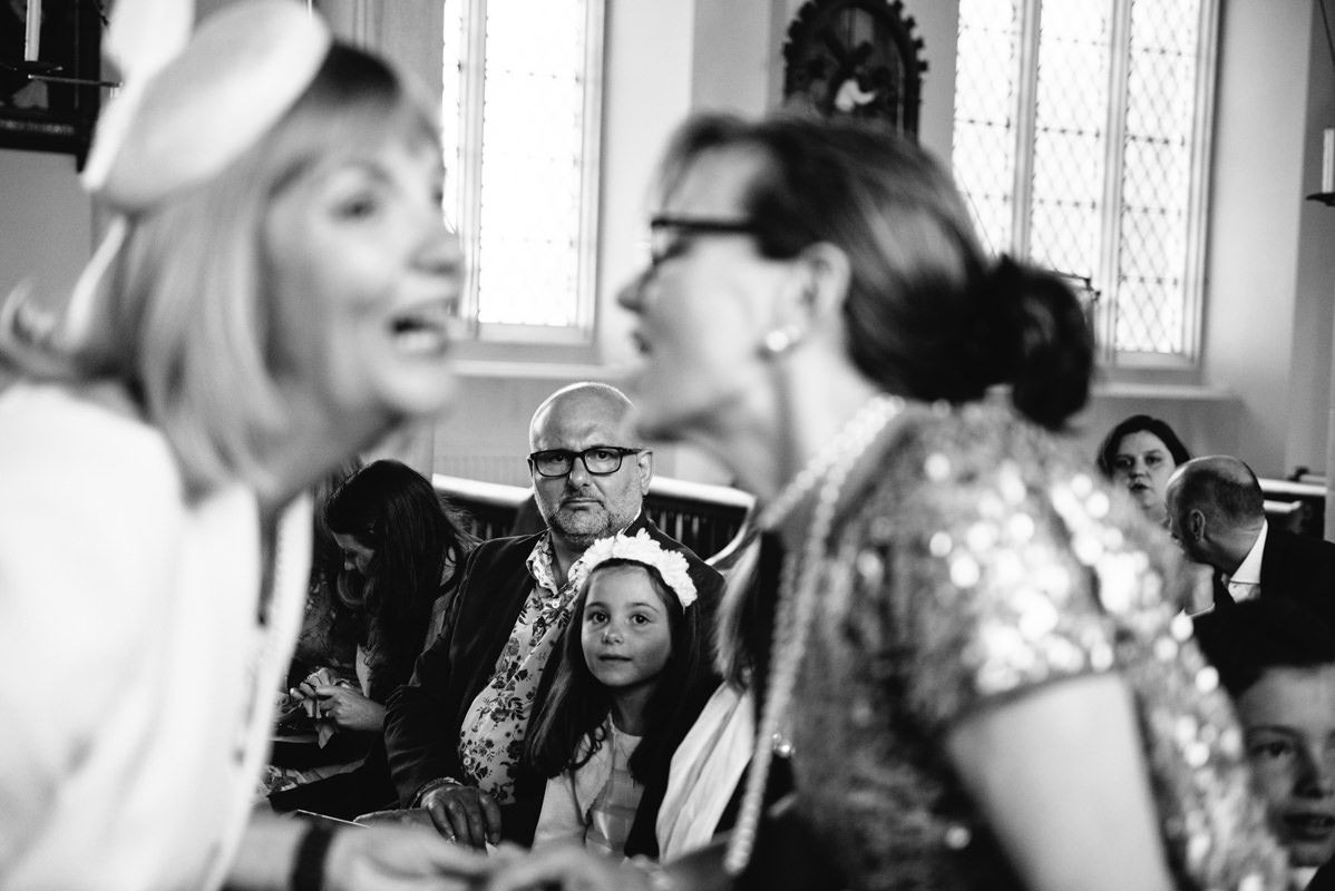 Candid black and white shot of wedding guests laughing during celebration.