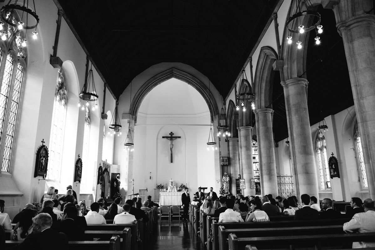 Interior of a traditional church with arched ceilings and rows of pews during a ceremony.
