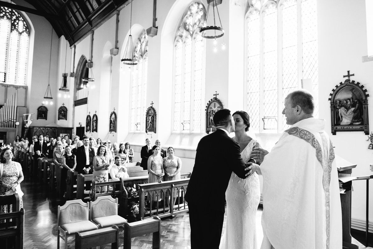 A wedding ceremony takes place in a grand church with Gothic architecture and stained glass windows.