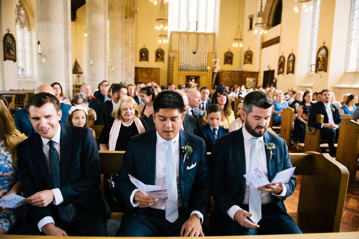 Wedding guests follow along in hymnals during a church ceremony.