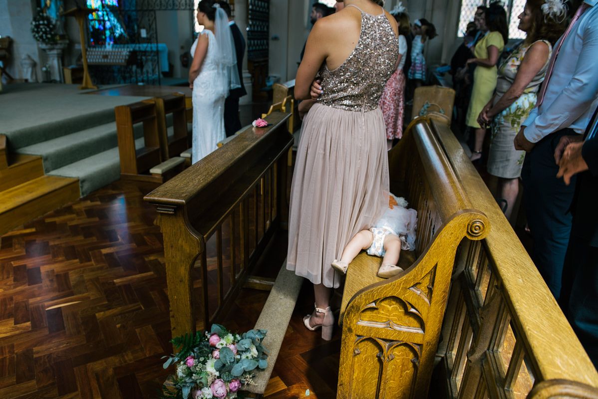Detail shot of church pews and guests during a wedding ceremony.